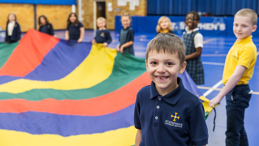 Smiling Catholic school students playing with a parachute in gym class