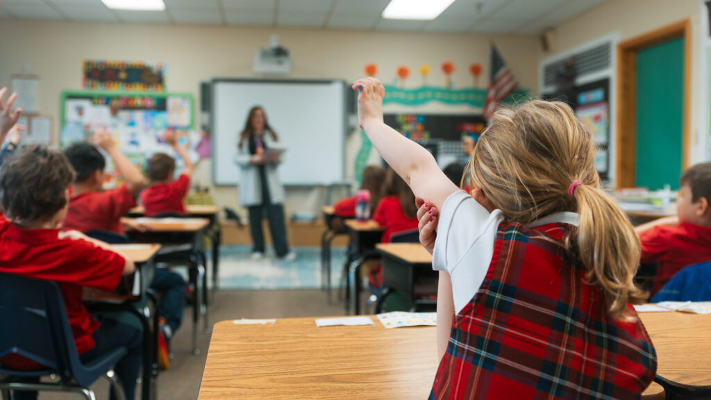 Catholic school student raising hand in classroom